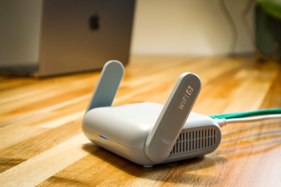 Biały router z dwiema antenami i napisem WiFi 6 na biurku