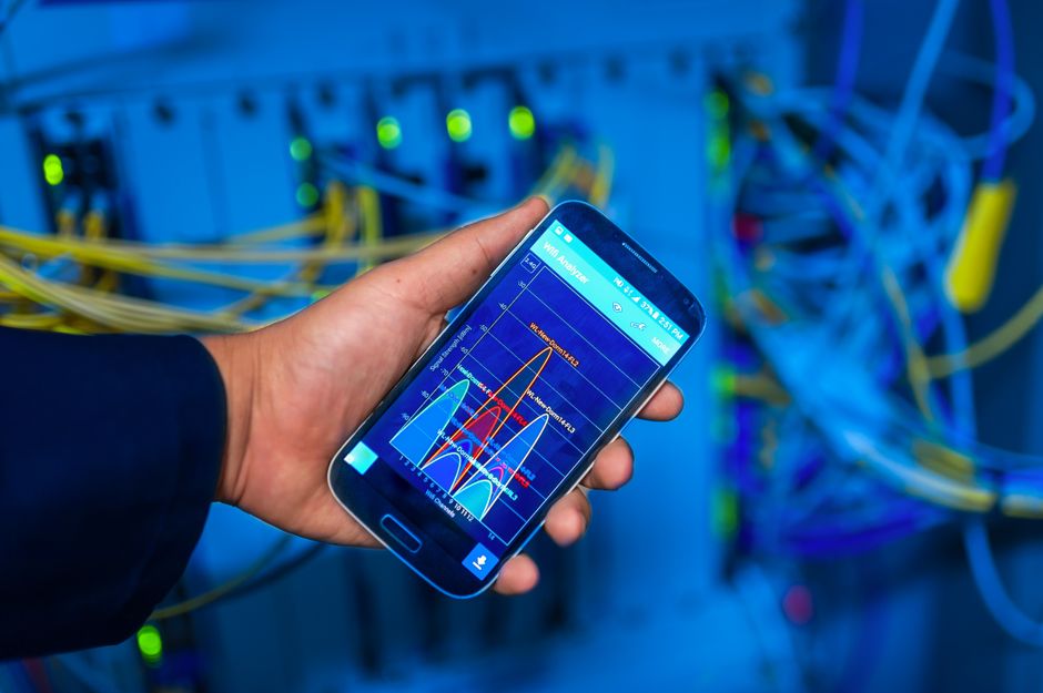 Dłoń trzymająca smartfon z aplikacją do analizy sygnału sieci Wi-Fi.