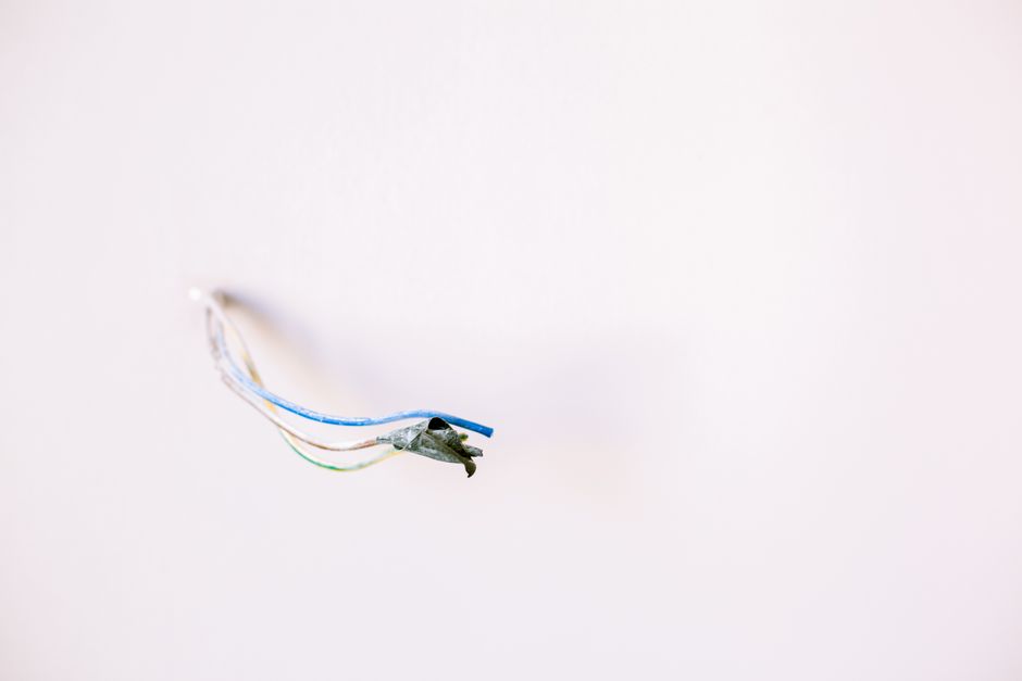 Wystające ze ściany trzy kolorowe przewody elektryczne z uszkodzoną izolacją