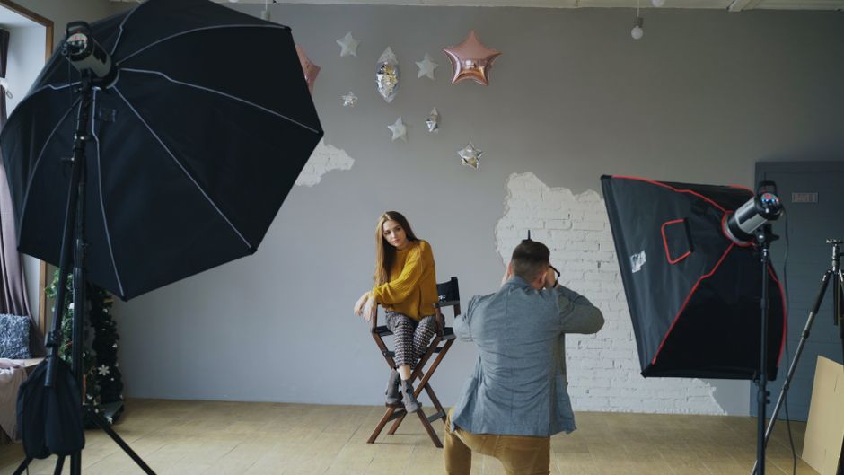 Fotograf robiący zdjęcie modelce w studio z użyciem dwóch lamp błyskowych