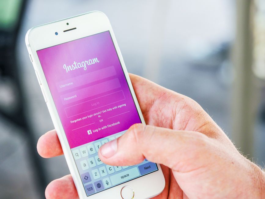 Dłoń trzymająca smartfon z otwartym ekranem logowania do aplikacji Instagram.