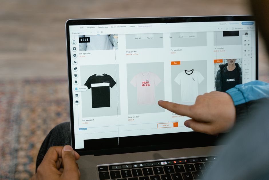 Osoba wskazująca palcem na ekran laptopa z siatką produktów sklepu internetowego
